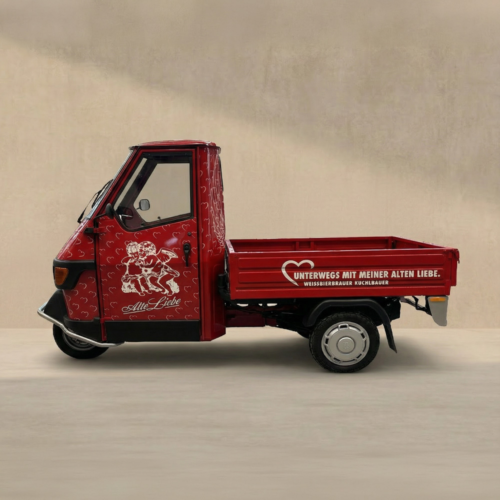 Gesamt-Profiil-Ansicht einer roten Apé mit einer vollflächigen Herzen-Beklebung und auf der Tür eine Illustration von zwei Engel, darunter eine silberne Aufschrift mit eine geschwungenen mit 